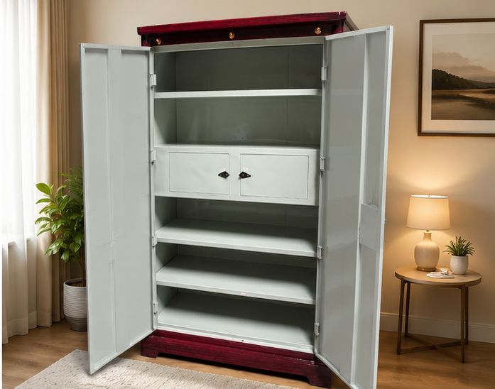 A tall white metal storage cabinet with two doors open, showing multiple shelves and two small front drawers. The cabinet stands in a warmly lit room with curtains, a plant, a side table with a lamp, and framed wall art.