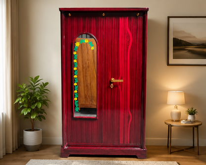 A tall, red wooden wardrobe or armoire with a glossy finish, featuring a decorative arched mirror on the front with a colorful floral border, set in a styled room with a plant, side table, and lamp.