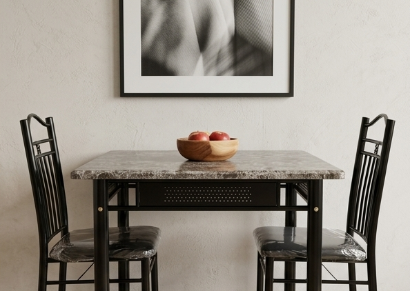 Dining table with marble top and black metal chairs, apples in a bowl on the table, framed artwork on the wall.
