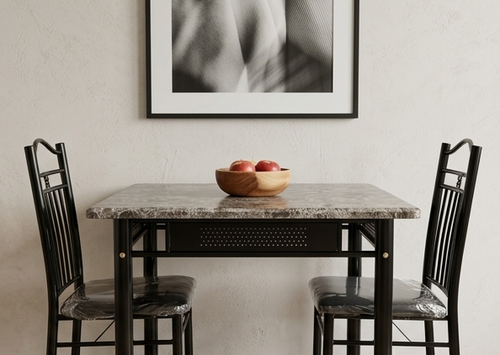 Dining table with marble top and black metal chairs, apples in a bowl on the table, framed artwork on the wall.