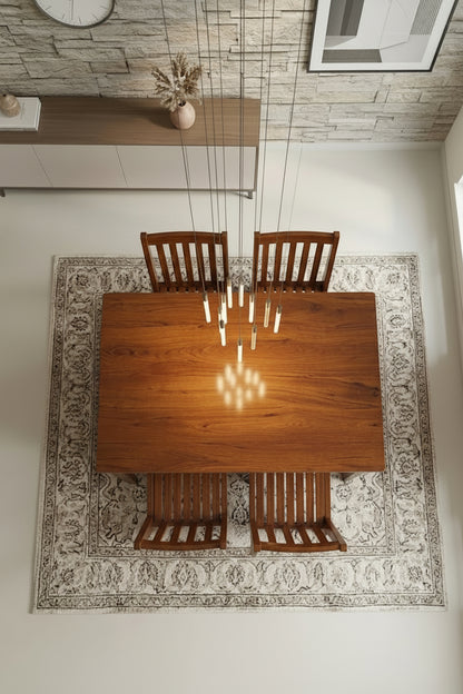Wooden dining table with four chairs in a room with a patterned rug and stone wall.