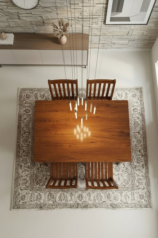 Wooden dining table with four chairs in a room with a patterned rug and stone wall.