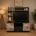 A modern TV stand and media console in a styled living room. The unit features a black marble-look front with warm beige and brown veining, a black marble-look back panel with vertical wood slats, a wooden floating shelf, and a central screen recess.