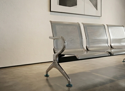 Metallic bench in a room with a textured wall and framed picture.